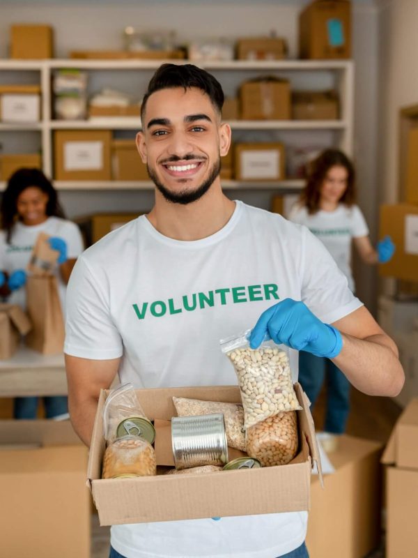 young-arab-volunteer-working-at-charity-center-holding-food-donation-box-and-smiling-to-camera.jpg